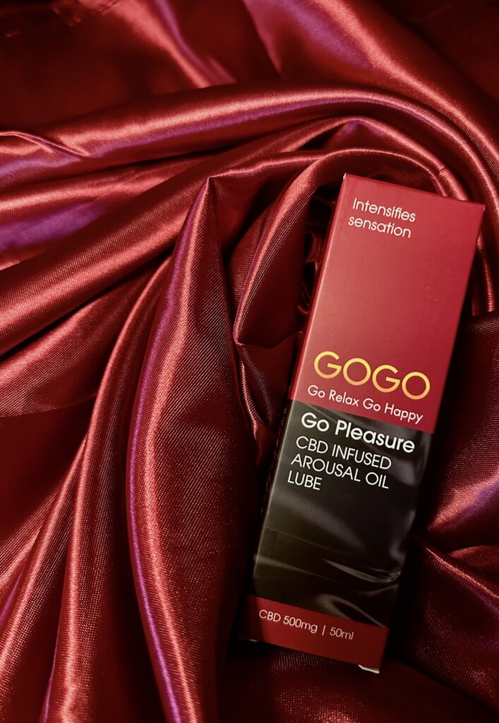 GOGO CBD oil arousal lube resting on burgundy silk fabric